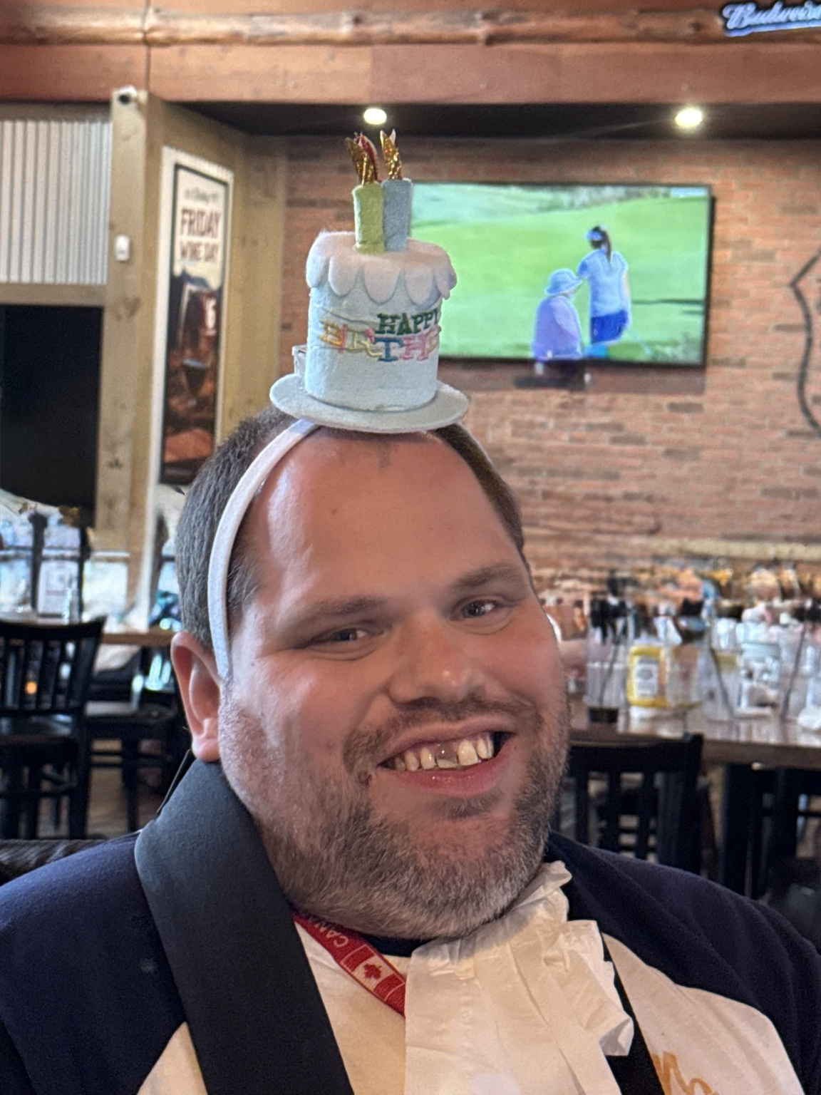 Jeff smiling at a restaurant while wearing a Happy 19 birthday-cake headband.
